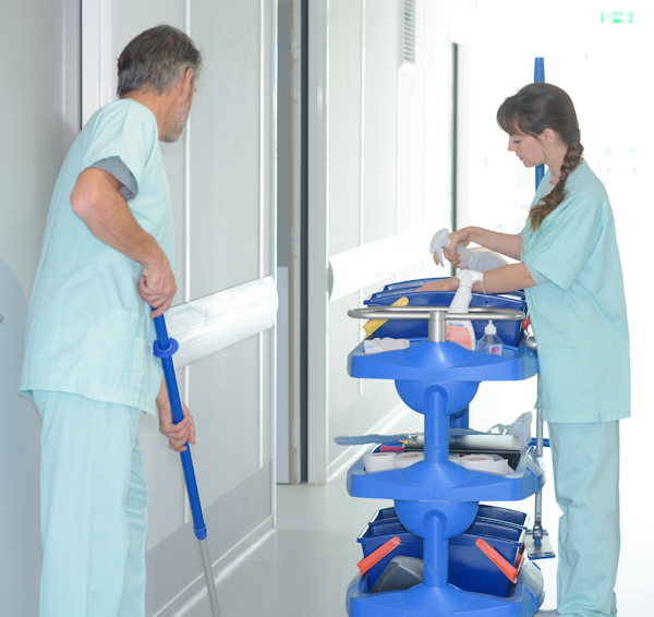 Janitorial staff mopping and cleaning hospital hallway.