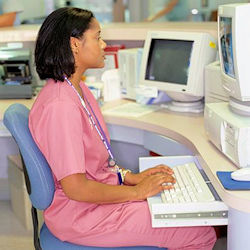 A nurse sitting at work station typing on a computer.