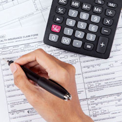 A person filling forms for a health plan with a calculator on the desk top.