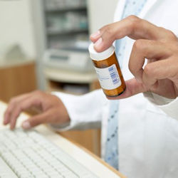 A pharmacist holding a bottle of prescription medicine.