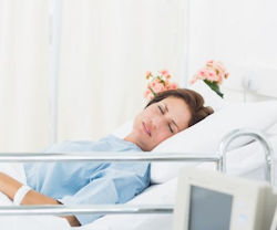 Patient in pain, laying in a hospital bed.