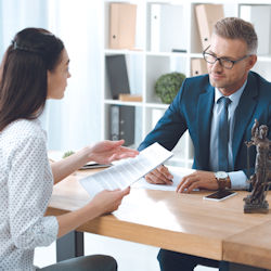 Doctor and person sitting at a desk speaking to one another.