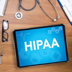 A computer tablet laying on a desk with the word HIPAA on the screen.