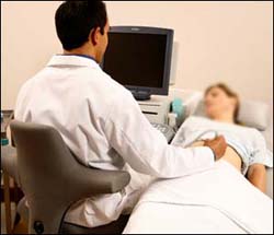 Sonographer using machine to scan patient.