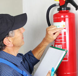 Worker checking a wall mounted fire extinguisher.