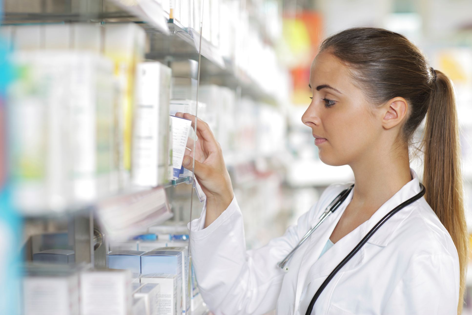 Pharmacist looking at prescription medicine on shelf.