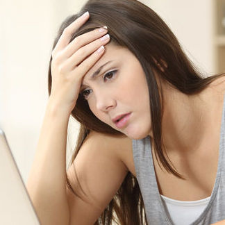 a lady looking at a screen with her head in her hand