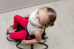 Overhead view of a child in wheelchair wearing a facemask.