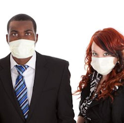 A man and a woman in suits standing wearing face masks.