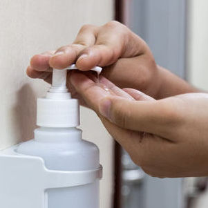 Child using one hand to pump hand sanitizer into the other hand.