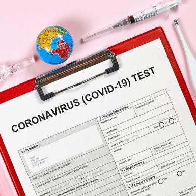 A COVID-19 test form on top of a red clipboard.
                                        There is a thermometer, a syringe, a small globe, and a mask around the clipboard.