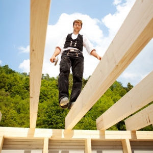 Image of employee walking on a 2x6 beam about 8 ft above the ground no fall protection