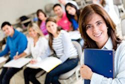 A classroom of students and a teacher all looking at the camera and smiling.