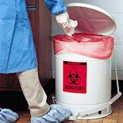 Healthcare provider placing contaminated material into a biohazard waste can.