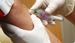 Healthcare provider wearing gloves and giving a shot to a patient in their arm.