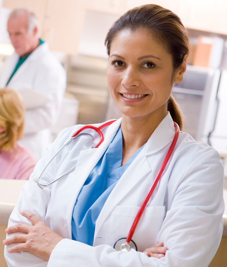 Healthcare provider with a stethascope around her neck looking at the camera. Two other medical workers in the background