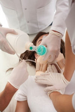 Healthcare workers administering aid to a woman laying on the floor.