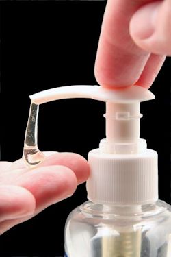 Hand pushing top of hand gel dispenser