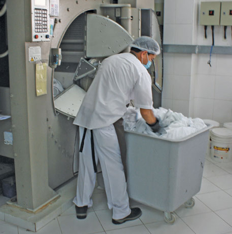 Employee wearing PPE washing laundry.