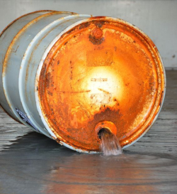 Overturned metal barrel with fluid spilling out