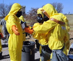 Two workers helping with decontamination of a third worker