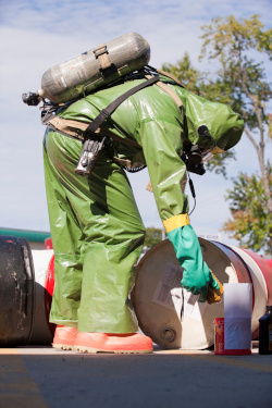 Worker in full PPE performing field activity and learning how to use air  monitoring equipment