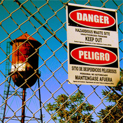 Sign showing danger hanging on fence surrounding hazardous waste site