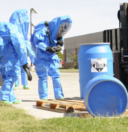 Two workers  inspecting a barrel of hazardous chemicals