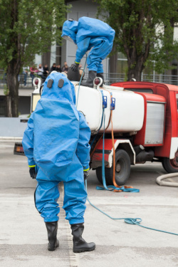 Two workers in full PPE standing beside a truck with a tank participating in a chemical spill training