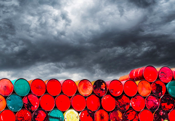 Thirty or more barrels stacked with stormy sky in background