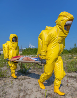 Two workers in fully encapsulated PPE carrying a stretcher 