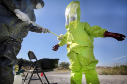 Worker in Level A protective suit being scrubbed down during decontamination