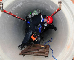 Worker in chemical protective clothing entering a confined space