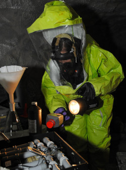 Worker in chemical protective clothing in a dark confined space