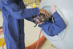 Worker wearing a respirator entering a tight confined space