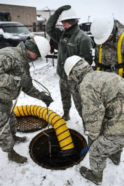 Workers using force air ventilation to ventilate a confined space