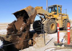 Heavy equipment dumping dirt into trench