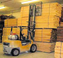 Unattended Forklift with forks lowered in front of a large stack of wood