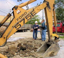 Workers standing near an excavator