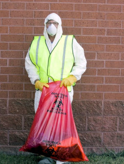 man in protective suit handling bag of infectious waste