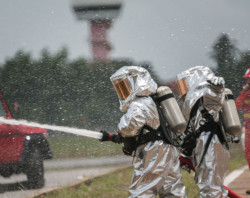 Emergency response teams suited up with PPE using hose to spray hazard