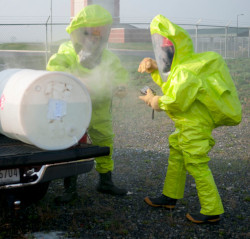 Two workers in Level A protective gear responding to leaking barrel