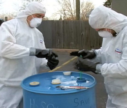 two workers outdoors performing drum sampling