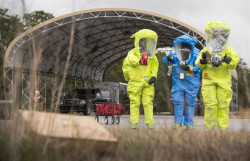 Three men in hazard suits at a decontamination station