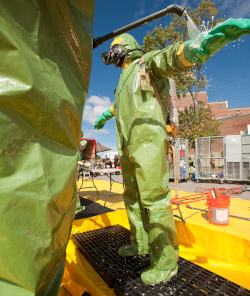 A person in a green protective suit is being decontaminated.