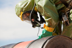 Hazmat Firefighter Examining A Chemical Drum