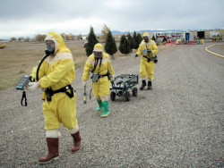 Three men in yellow hazmat suits perform an initial site evaluation