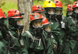 A group of people wearing green hazmat suits.