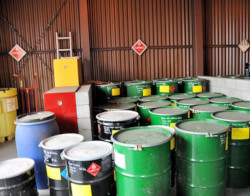 A group of large unlabeled green and black drums stored in a warehouse