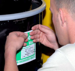 A man placing a label on a black drum.